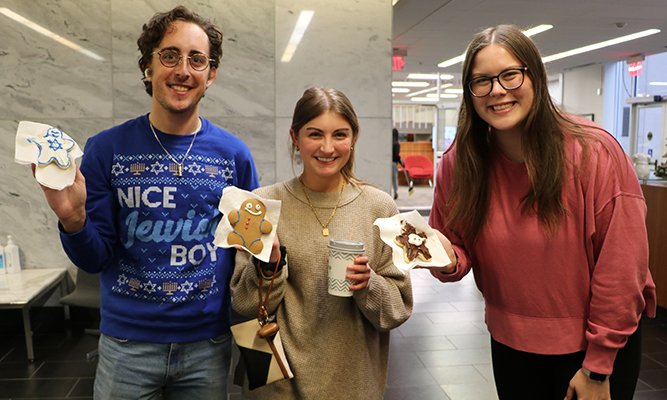 three students holding cookies