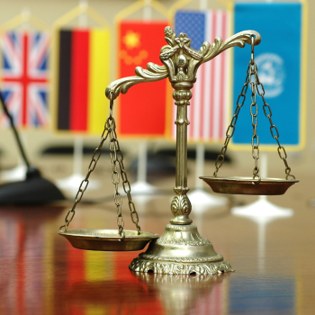 scales of justice in front of international flags